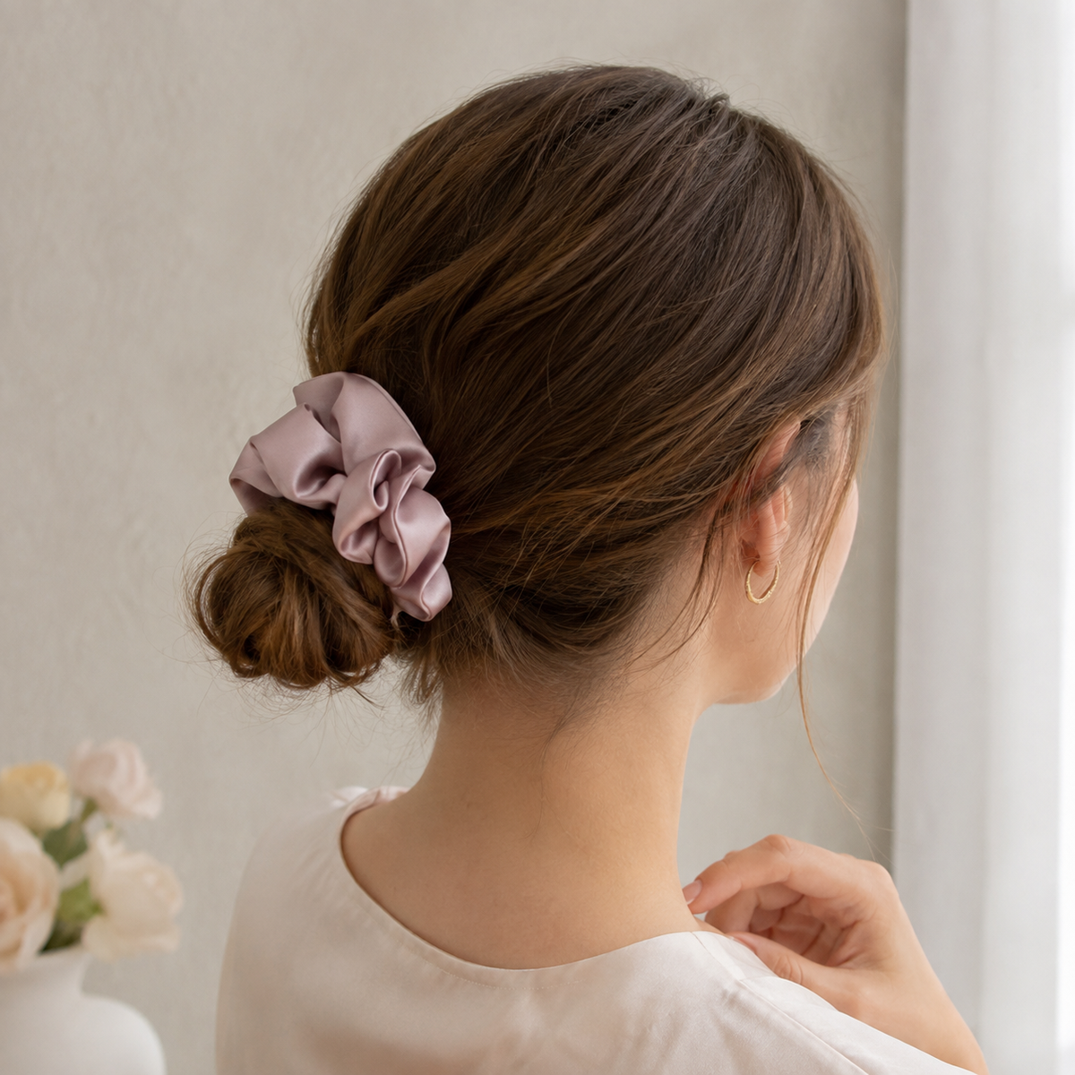 Chouchou rose poudré porté dans un chignon bas